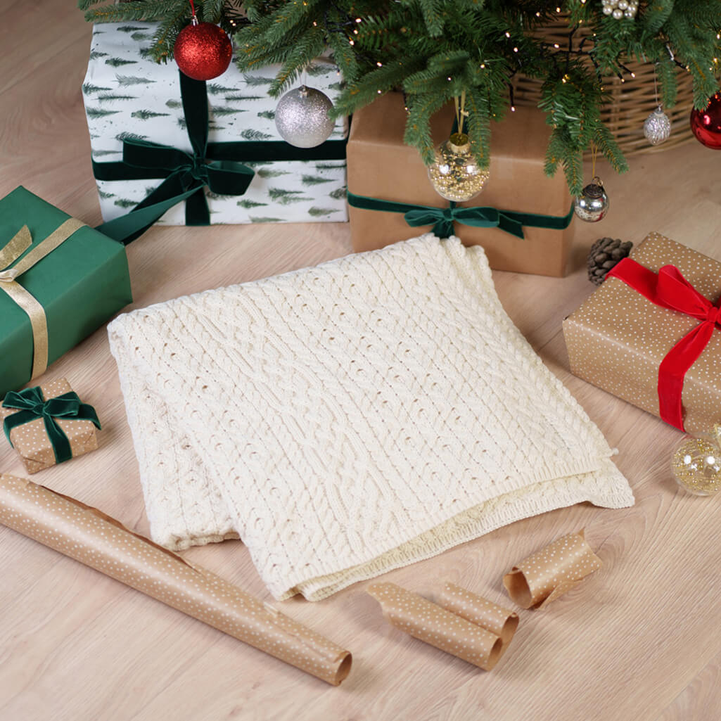 Traditional Aran Honeycomb Wool Throw - Cream Irish Wool Blanket Folded Under Christmas Tree with Wrapped Gifts