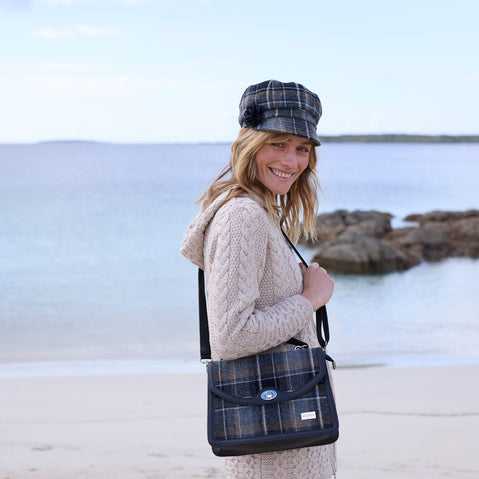 A woman wearing a beige Irish wool newsboy cap with a leather flower motif on the side.