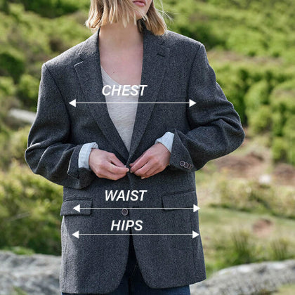 Person wearing a gray blazer with labeled measurements against a natural background