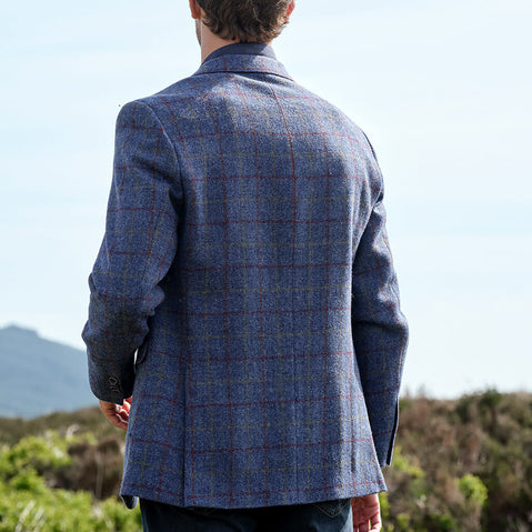 Person wearing a blue checkered jacket standing outdoors with mountains in the background