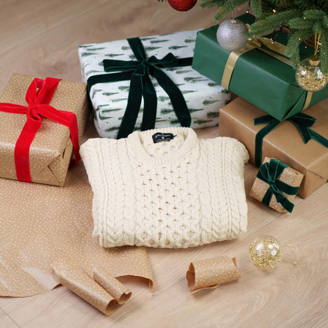Close-up detail of a cream Aran sweater showing traditional Irish cable knit patterns and texture, perfect for festive winter occasions