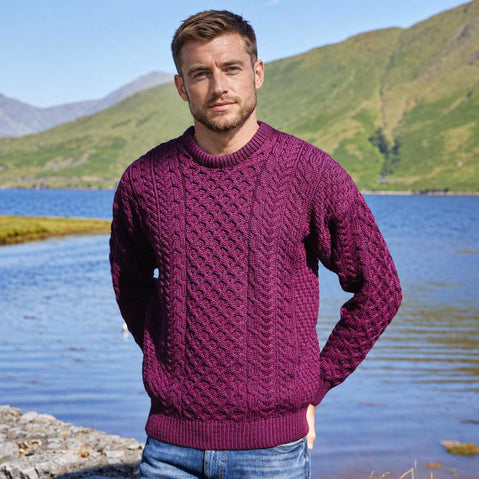 Image featuring the Men's Traditional Crew Neck Aran Sweater in damson, crafted with authentic Irish Aran cable knit patterns and a timeless crew neck silhouette, showcasing traditional Irish craftsmanship against a scenic lakeside mountain landscape.