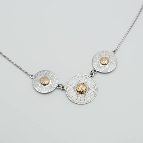Necklace with three circular medallions featuring gold centers on a light gray background