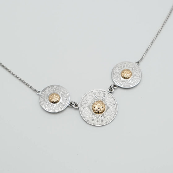 Necklace with three circular medallions featuring gold centers on a light gray background
