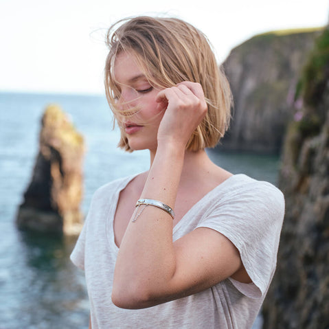 Side view of the Celtic Warrior Bangle, crafted with intricate Celtic knotwork and traditional Irish design details inspired by ancient Irish heritage, showcased against a rugged coastal landscape that highlights its timeless craftsmanship.