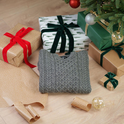 Grey traditional Aran sweater with cable knit patterns displayed with Christmas decorations and festive setting