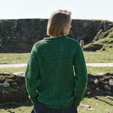 Back view of the Women's Traditional Fisherman Irish Wool Sweater in Valley Green, crafted from premium Irish wool with authentic fisherman knit texture, showcased in the scenic Irish countryside with rolling green landscapes and rugged natural surroundings.