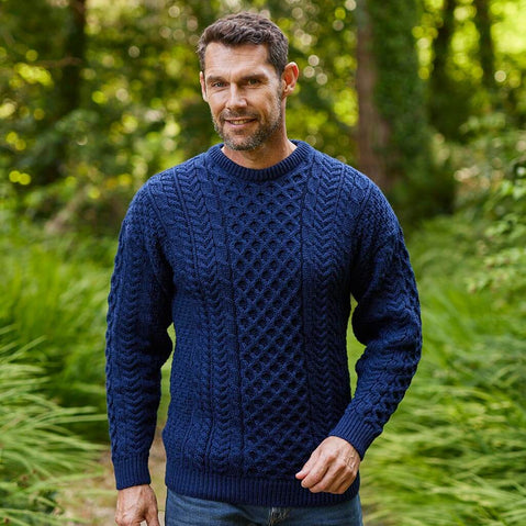 Man wearing a dark blue Aran sweater standing in a forest