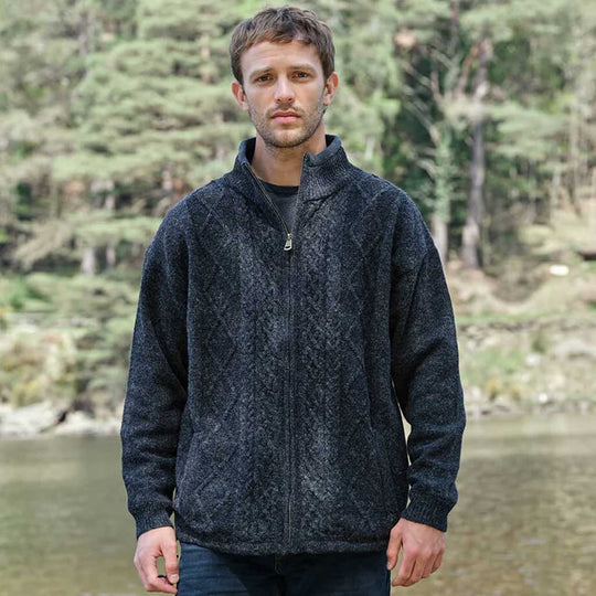 Man wearing a charcoal Men's Signature Lined Fisherman Zipper Cardigan standing by a body of water with trees in the background