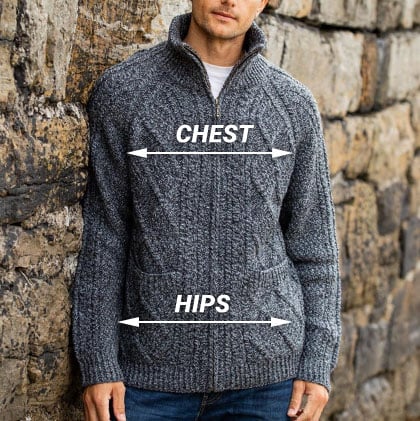 A man stands against a stone wall, wearing a gray knit sweater with a zip-up collar. The image includes labels indicating