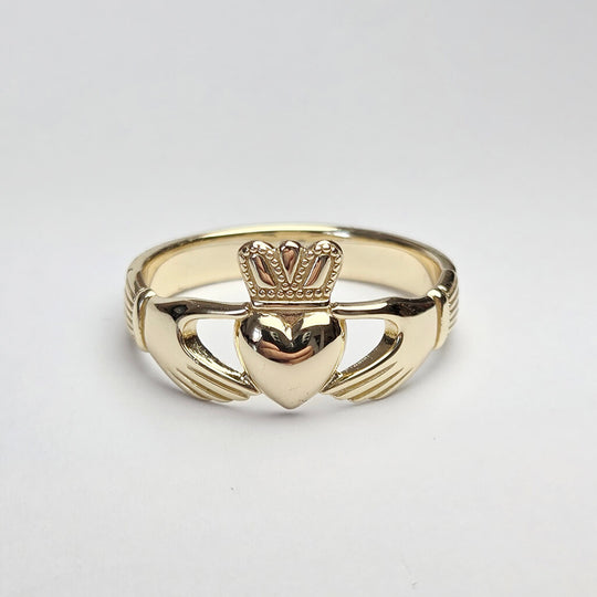 Gold Claddagh ring on a light gray background