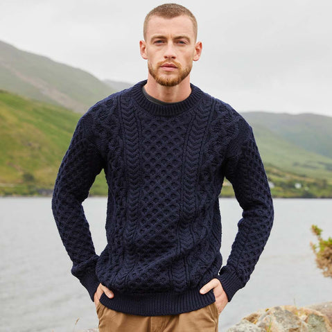 Man wearing a navy blue Men's Crew Neck Irish Wool Classic Sweater with a mountainous landscape in the background