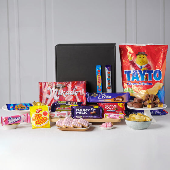 Assorted confectionery items including candy bars and snacks on a white surface with a gray background.