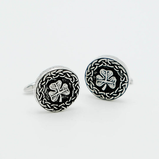 Pair of silver cufflinks with clover design on a white background