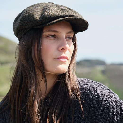 Woman wearing a flat cap outdoors with a blurred natural background