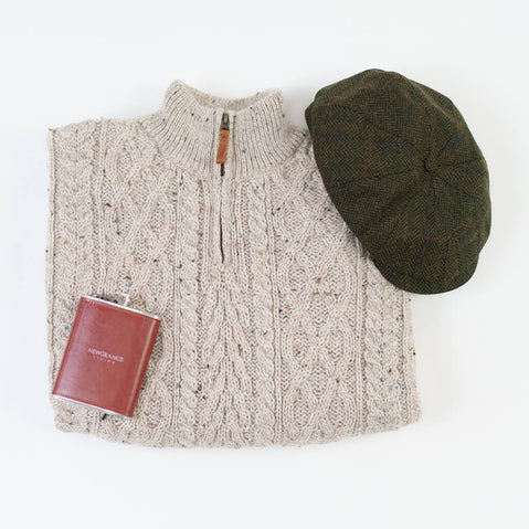 Beige cable knit zip-up sweater with wooden zipper pull, displayed with Men's Classic Irish Tweed Driving Cap in olive green and burgundy Newgrange Hip Flask Set