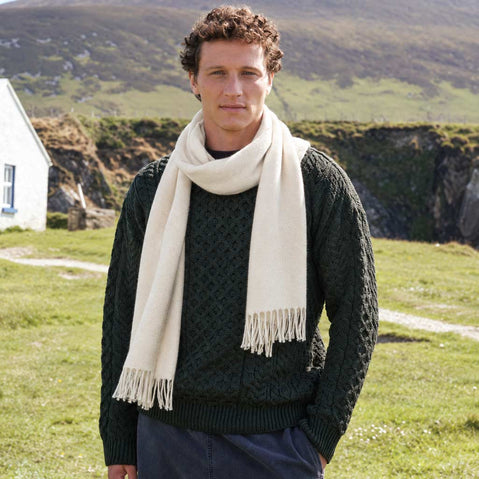 Men's Herringbone Lambswool Scarf in Beige, crafted from soft premium lambswool with a classic herringbone weave, styled outdoors in the Irish countryside alongside traditional Irish knitwear and rugged coastal scenery.