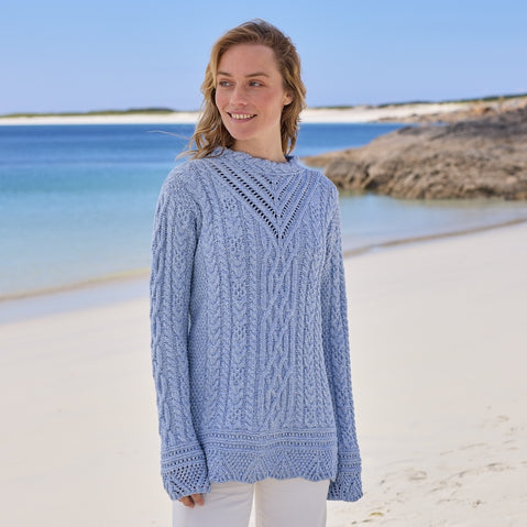 Woman wearing a blue Women's Signature Aran Tunic Sweater on a beach