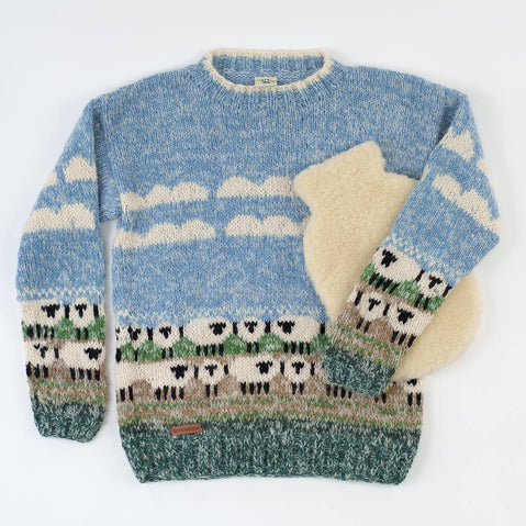 Unisex hand-knitted mohair sweater in light blue with white sheep pattern, cream stripes, and green grass detail at hem