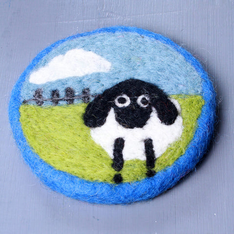Felted sheep patch with a blue sky and green field on a gray background