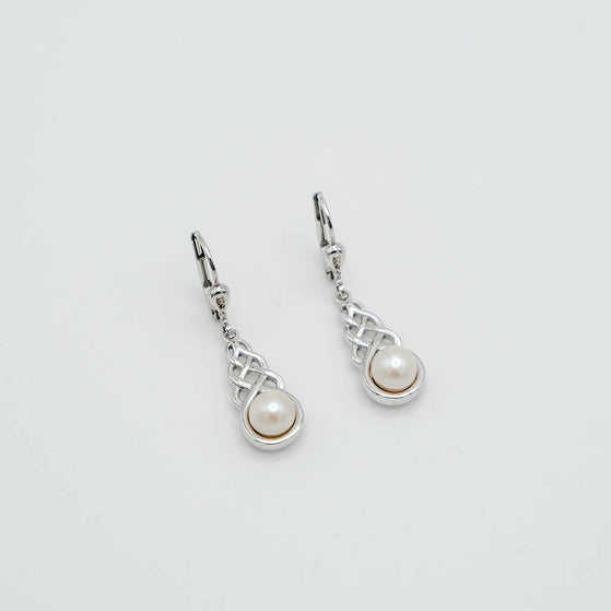 Pair of silver earrings with pearl drops on a light gray background