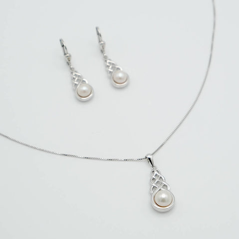 Pearl necklace and earrings set on a light gray background