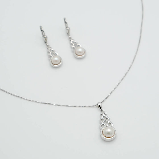 Pearl necklace and earrings set on a light gray background