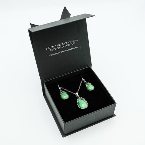 Green gemstone necklace and earrings set in a black box with text.