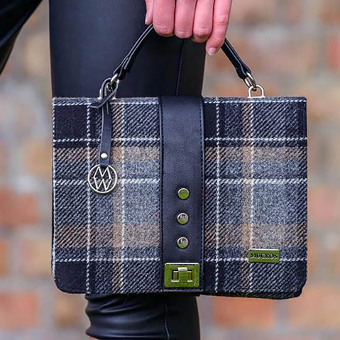 Plaid handbag with visible brand logo held by a person against a blurred background
