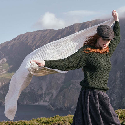 Image featuring the Traditional Aran Honeycomb Wool Throw in cream, crafted from premium wool with authentic Irish honeycomb knit patterns, showcasing timeless Aran craftsmanship against a breathtaking coastal backdrop inspired by Ireland's rugged landscape.