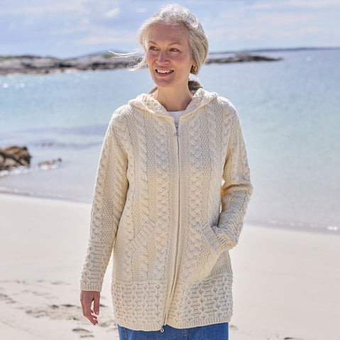Woman wearing a cream-colored Aran cardigan on a sunny beach
