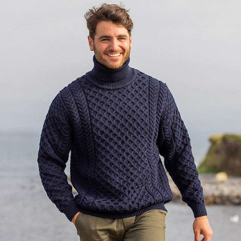 Man wearing a navy blue Men's Signature Fisherman Turtleneck Wool Sweater standing by a body of water.