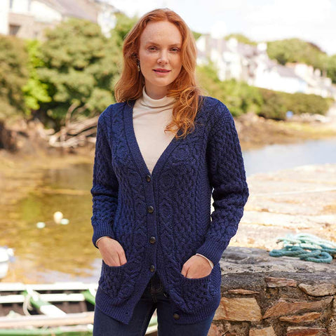Woman wearing a navy Women's Classic Aran Boyfriend Button-Front Cardigan by a waterfront