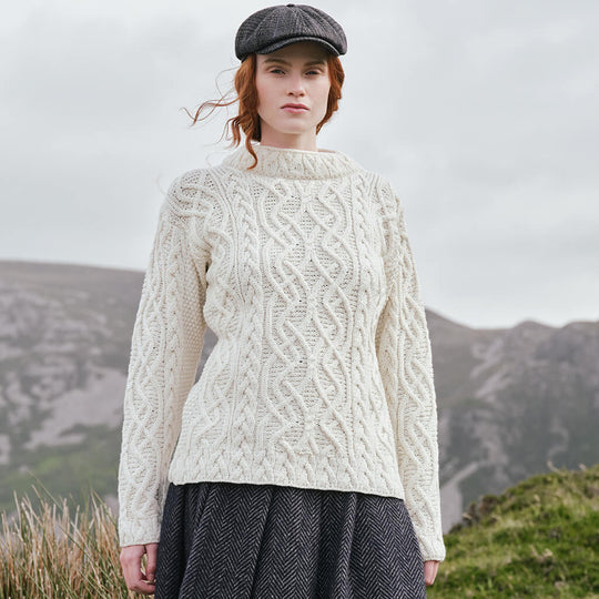 Image featuring the Women's Cable Knit Aran Tunic Sweater in cream, crafted with authentic Irish Aran cable knit patterns and an elegant funnel neck silhouette, showcasing timeless Irish craftsmanship inspired by Ireland's rugged countryside.