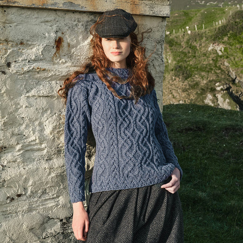 Image featuring the Women's Cable Knit Aran Tunic Sweater in denim blue, crafted with authentic Irish Aran cable knit patterns and a flattering tunic-length design, inspired by Ireland's rich knitting heritage and rugged landscapes.