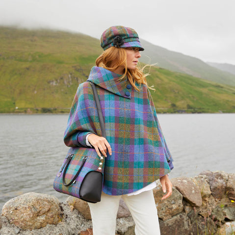 A woman wearing a beige Irish wool newsboy cap with a leather flower motif on the side.