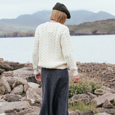 Back view of the Irish Tweed Fleck A-Line Skirt in navy, crafted from authentic Irish tweed with subtle multicolored flecks and a timeless A-line silhouette, showcased against Ireland's rugged coastline and mountain scenery.