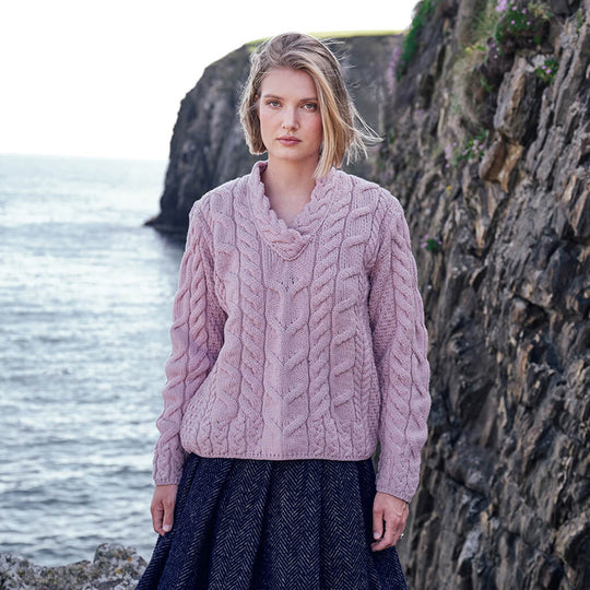 Image featuring the Men's Cable Knit Crew Neck Wool Sweater in pink, crafted from premium wool with authentic Irish cable knit patterns and a timeless crew neck silhouette, showcased against Ireland's dramatic coastal scenery.
