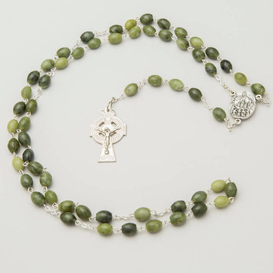A rosary with green Connemara marble beads and a nickel Celtic cross centerpiece, finished with a silver-colored medal.