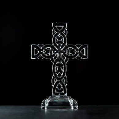 Irish home décor. A clear glass Celtic cross ornament with intricate knot detailing, displayed against a black background.