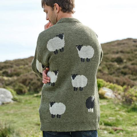 Person wearing a green sweater with sheep pattern in a natural setting