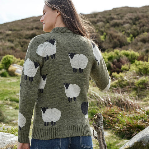 Person wearing a green sweater with sheep pattern in a natural setting