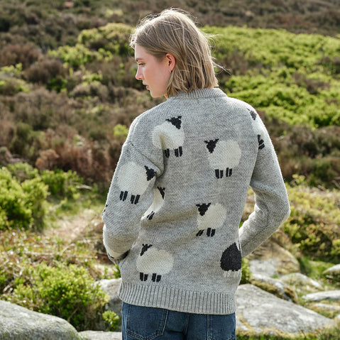 Person wearing a gray sweater with sheep pattern in a natural setting