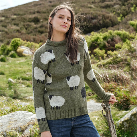 Woman wearing a green sweater with sheep patterns in a natural setting