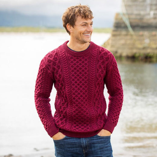 Man wearing claret crew neck Irish wool Aran sweater with traditional cable knit patterns