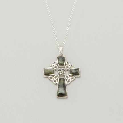 A silver Celtic cross pendant hangs from a delicate chain. The cross features intricate knotwork and a sun design at the center. The background is neutral, highlighting the pendant's details.
