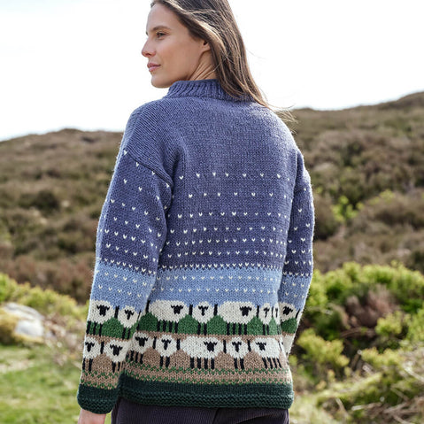 Woman wearing a blue Aran sweater with sheep pattern in a natural setting