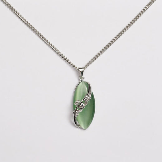 A Claddagh pendant with a green cat's eye stone and silver detailing, attached to a silver chain.