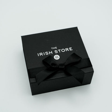 Black gift box with a bow and 'The Irish Store' branding on a light gray background