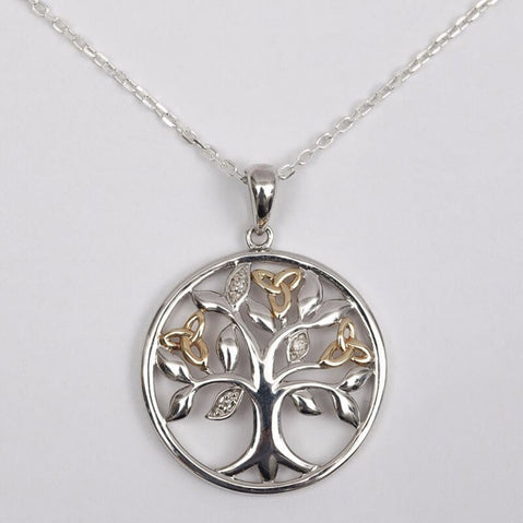 A sterling silver pendant with a Celtic Tree of Life design, featuring gold Trinity knots and diamond-set leaves on a chain.